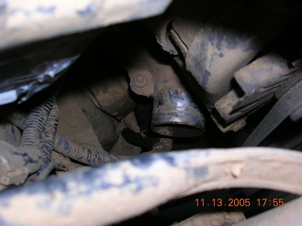 Muddy engine bay close-up of a cut rubber intake tube and wiring