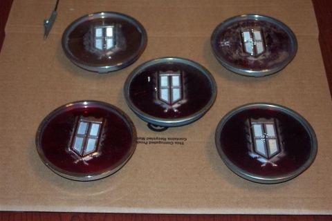 1985 Ford LTD Crown Victoria - Five car emblems with a shield and cross design are displayed on a cardboard surface.