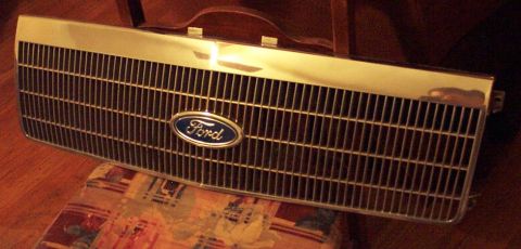1985 Ford LTD Crown Victoria - A Ford grille with the iconic blue oval emblem is shown resting on a patterned surface.