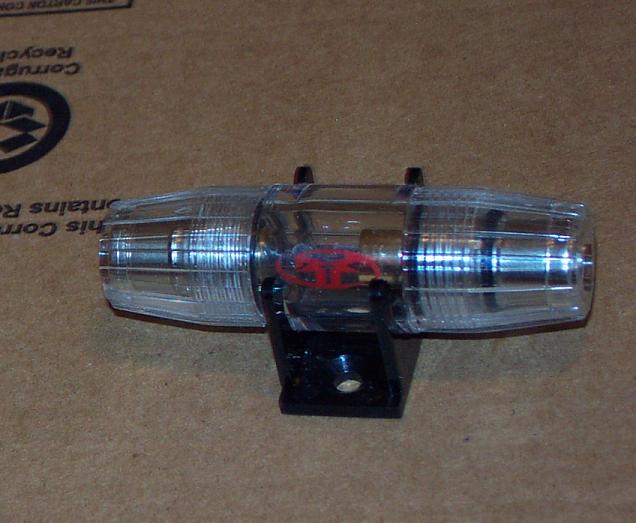 In-line fuse holder with red logo, mounted on black base, against cardboard