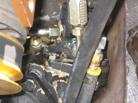 1994 Ford Bronco - A close-up view of a vehicle's power steering assist cylinder and associated plumbing.