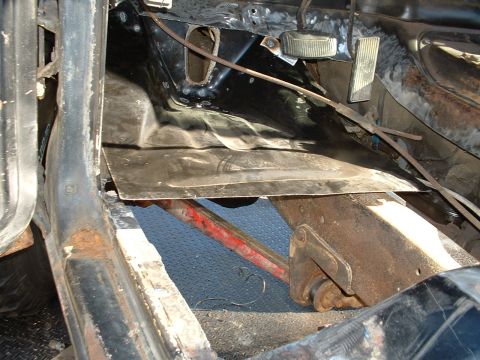 1978 Ford Bronco - The interior floor pan shows signs of rust and a hastily applied metal patch, with brake and gas pedals visible.