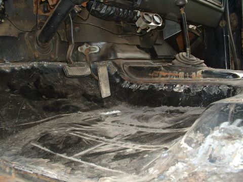 1978 Ford Bronco - The interior floor and pedals of a vehicle are visible, with signs of rust and wear.