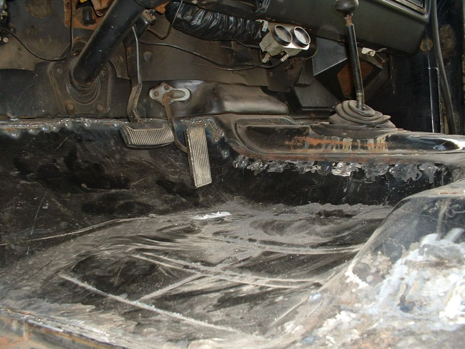 Interior floor and pedals of a vehicle, showing rust and wear
