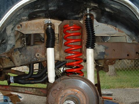 1978 Ford Bronco - The image shows the rear suspension system of a vehicle, including bright red coil springs and white shock absorbers.