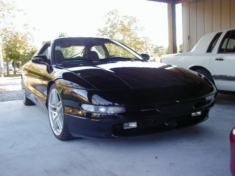 1994 Ford Probe - A black Ford Probe is parked under a carport next to a white sedan.