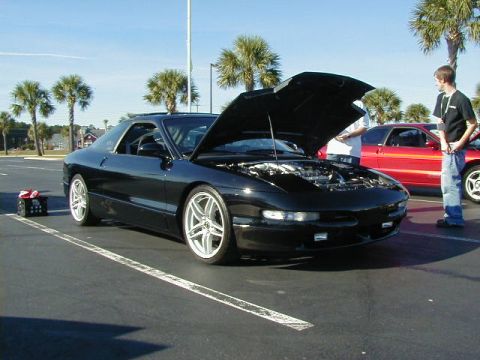 1994 Ford Probe - A black 1994 Ford Probe is displayed with its hood open, alongside another vehicle in a parking lot.