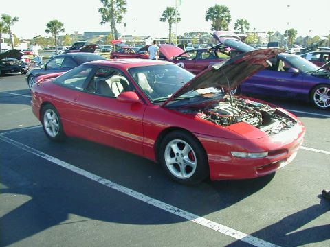 1994 Ford Probe - A red 1994 Ford Probe is parked with its hood open, revealing the engine bay. Other vehicles are visible in the background.
