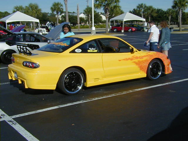 Yellow 1994 Ford Probe with flame graphics and a large rear spoiler parked in a lot