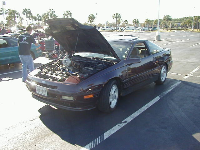 Dark purple 1993 Ford Probe with hood open, showing a turbocharger. The car is in a parking lot