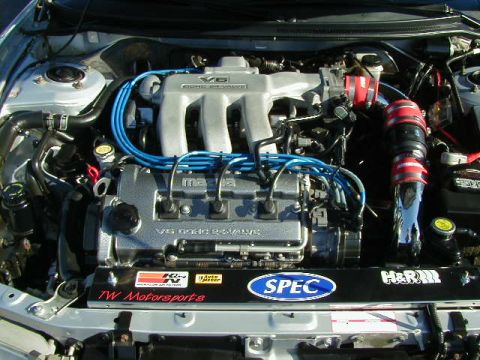 1994 Ford Probe - Engine bay of a silver car with a V6 DOHC engine and various aftermarket modifications visible.