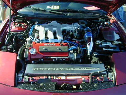 1994 Ford Probe - The engine bay of a red car displays a V6 engine with custom racing modifications and branding.
