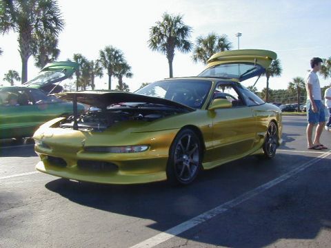 1994 Ford Probe - A yellow 1994 Ford Probe is parked with its hood and trunk open, alongside another car.