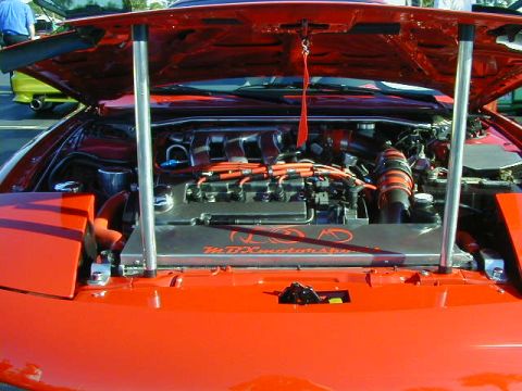 1994 Ford Probe - The engine bay of a red car is open, revealing a customized engine with orange wiring and accents.