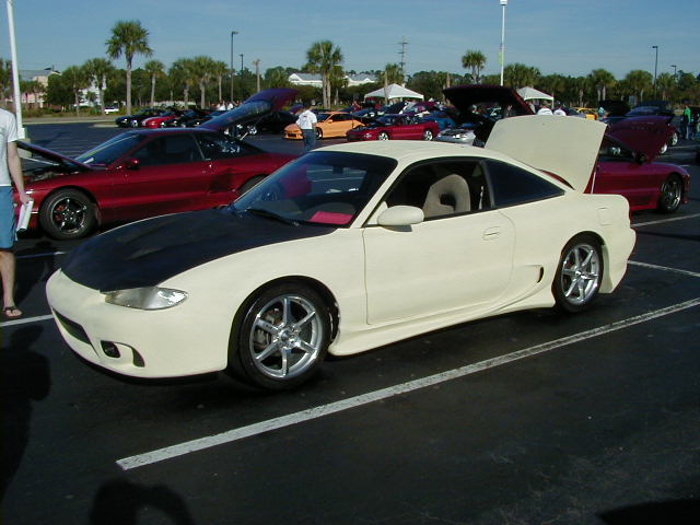 Cream-colored coupe with black hood, custom body kit, and aftermarket wheels