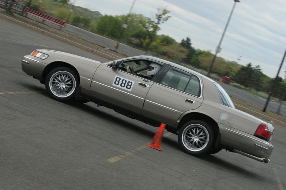 Gold Mercury Grand Marquis sedan with #888 door number cornering at autocross