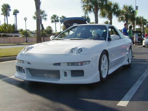 1994 Ford Probe - White coupe with aftermarket body kit, front-left view, parked in lot with palm trees.