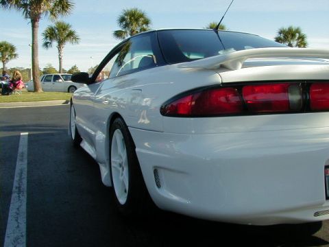 1994 Ford Probe - A white sports coupe is parked in a lot, with palm trees and another vehicle visible in the background.