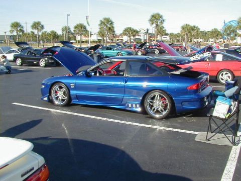 1994 Ford Probe - A blue 1994 Ford Probe GT is displayed with its hood open at a car show, surrounded by other vehicles.