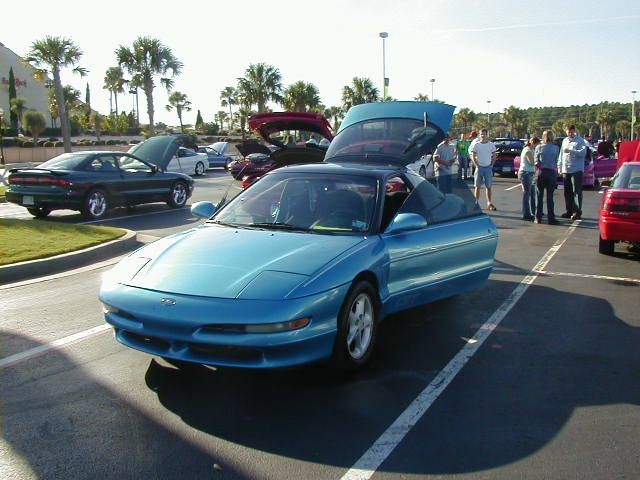 Blue 1994 Ford Probe with doors and hood open, parked in a lot with other cars