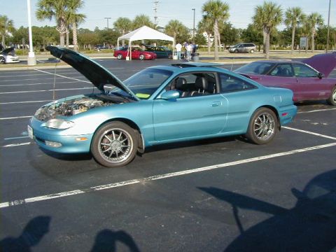 1994 Ford Probe - A blue coupe with its hood open is parked in a lot next to a purple car.