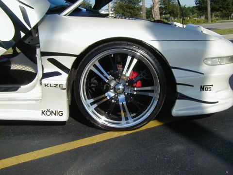 1994 Ford Probe - A white 1994 Ford Probe is shown from the front quarter angle, highlighting its custom wheels and racing decals.
