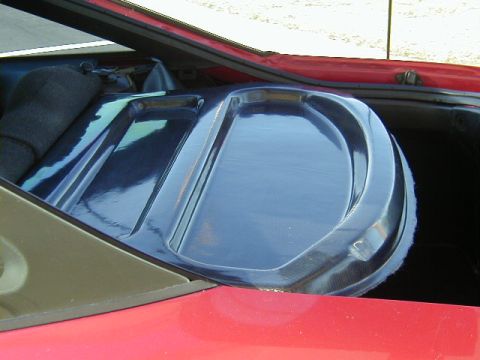 1994 Ford Probe - The rear interior of a car shows a blue speaker cover with a textured edge, set against red body panels.