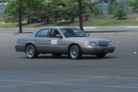 2001 Mercury Grand Marquis - A 2001 Mercury Grand Marquis, identified by its distinctive grille and body style, navigates a course with racing numbers displayed on its…