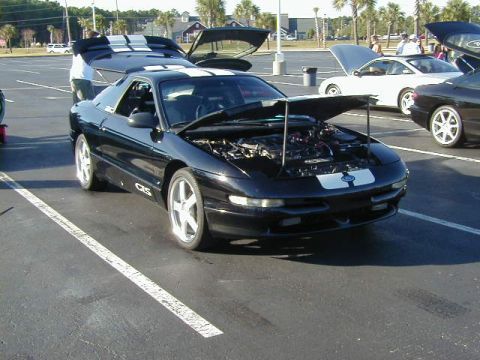 1994 Ford Probe - A black Ford Probe with racing stripes is parked in a lot with its hood open, revealing the engine.