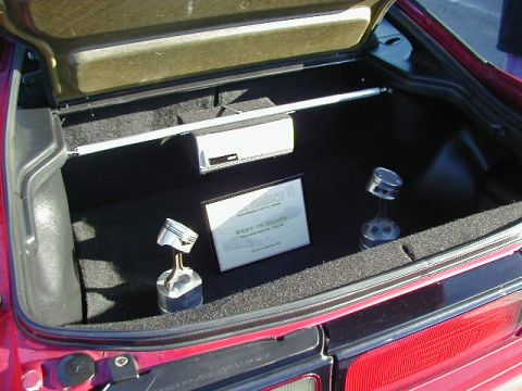 1994 Ford Probe - The trunk of a red 1994 Ford Probe displays two piston trophies and an award plaque.
