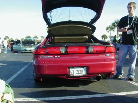 1994 Ford Probe - A red 1994 Ford Probe is shown from the rear with its trunk open, parked at an outdoor event.