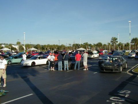 1994 Ford Probe - A gathering of cars and people in a parking lot under a clear blue sky.