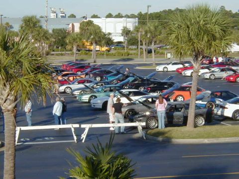 1994 Ford Probe - A gathering of cars in a parking lot with several people present.