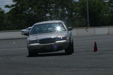 2001 Mercury Grand Marquis - A gold Mercury Grand Marquis navigates a course marked by traffic cones on a sunny day.