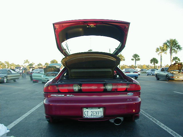 Red 1994 Ford Probe with trunk and hood open, parked in a lot with other cars