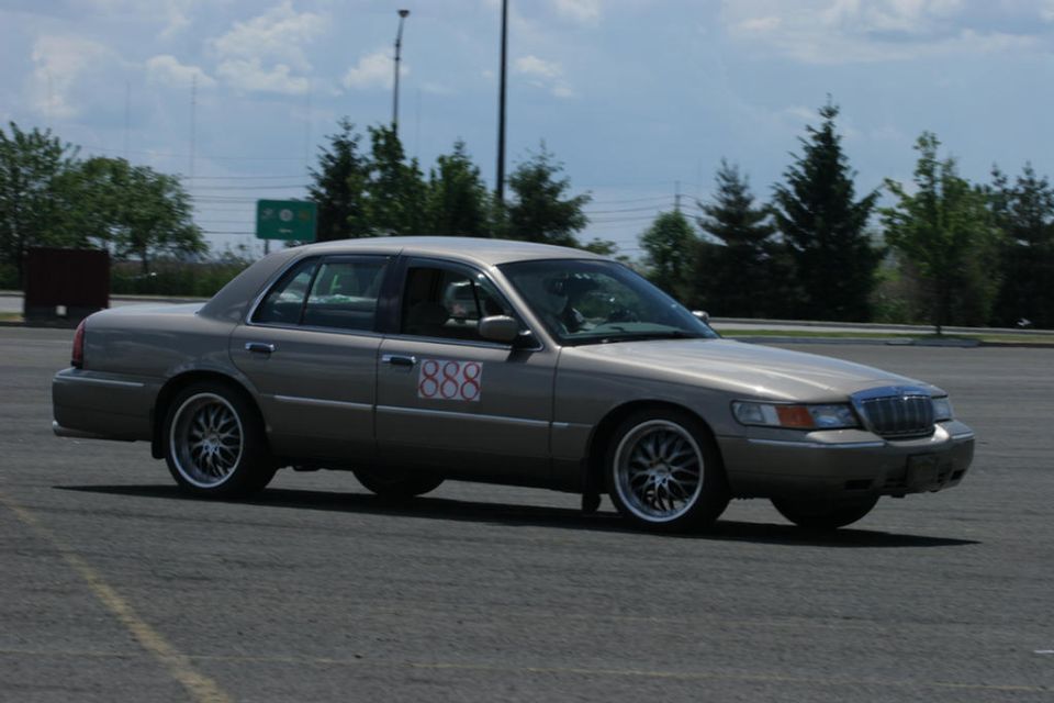 Tan 2001 Mercury Grand Marquis with white '888' racing numbers on the door, driving on asphalt
