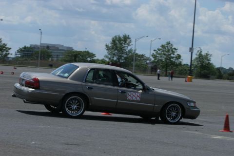 2001 Mercury Grand Marquis - A tan 2001 Mercury Grand Marquis navigates a course marked by orange cones on a cloudy day.