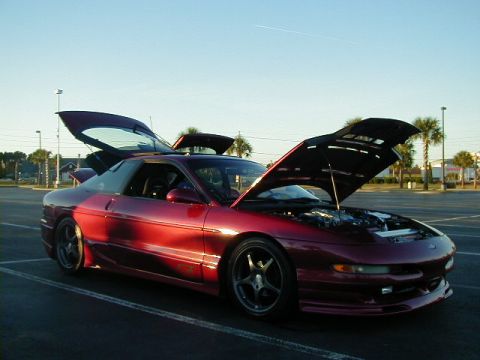 1994 Ford Probe - A red 1994 Ford Probe is parked with its hood and trunk open under a clear sky.
