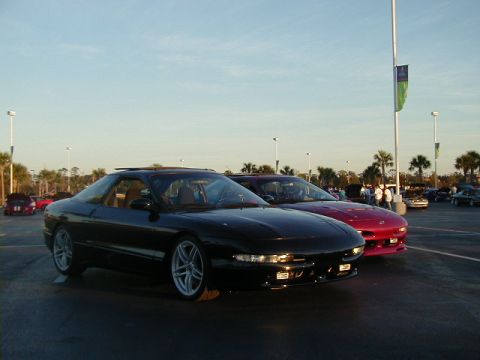 1994 Ford Probe - Two coupes are parked in a lot with palm trees and streetlights visible.