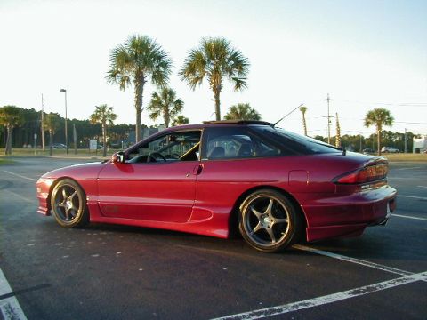 1994 Ford Probe - A red 1994 Ford Probe is parked in a lot with palm trees in the background.