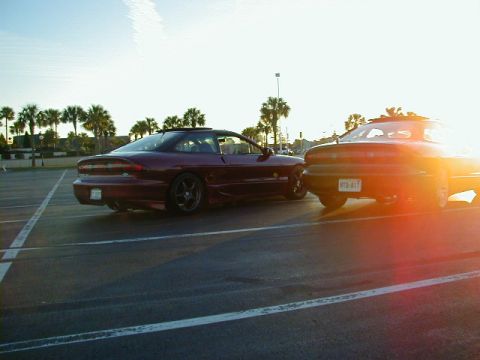 1994 Ford Probe - Two 1994 Ford Probes are parked in a lot, with the sun setting behind them.