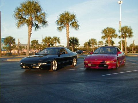 1994 Ford Probe - Two Ford Probes are parked in a lot under palm trees, with a website URL visible at the bottom right.