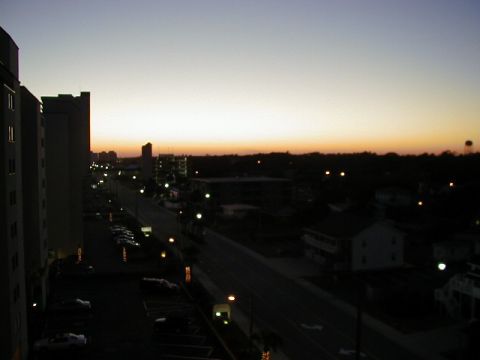 1994 Ford Probe - View of a city street and parking lot during twilight, with buildings silhouetted against the sky.