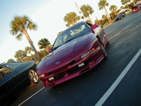 1994 Ford Probe - A red 1994 Ford Probe is parked in a lot with other vehicles and palm trees.