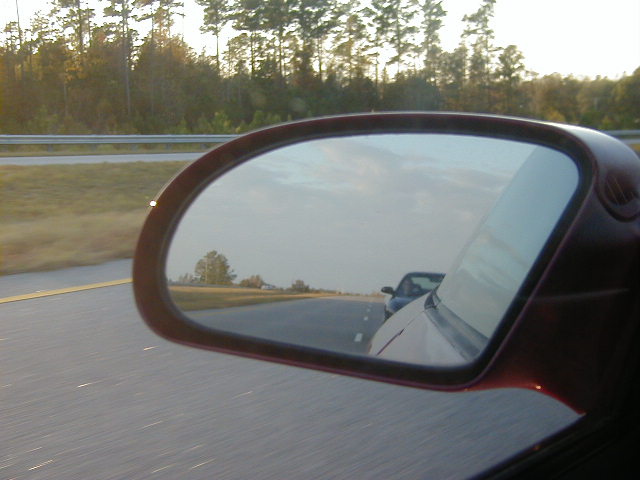 Reflection in side mirror shows another car on the highway