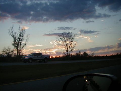 1994 Ford Probe - A pickup truck travels down a highway during a dramatic sunset with scattered clouds.