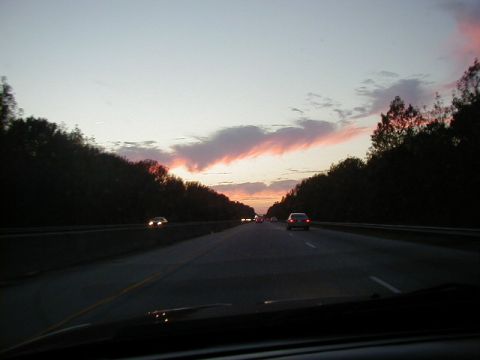 1994 Ford Probe - Cars drive on a highway during a colorful sunset with trees on either side.