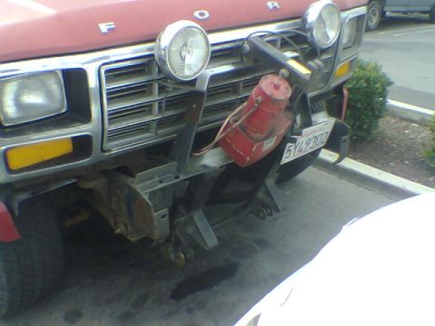 1988 Ford Bronco - The front of a red Ford truck, equipped with a winch and extra lights, is visible from the front.