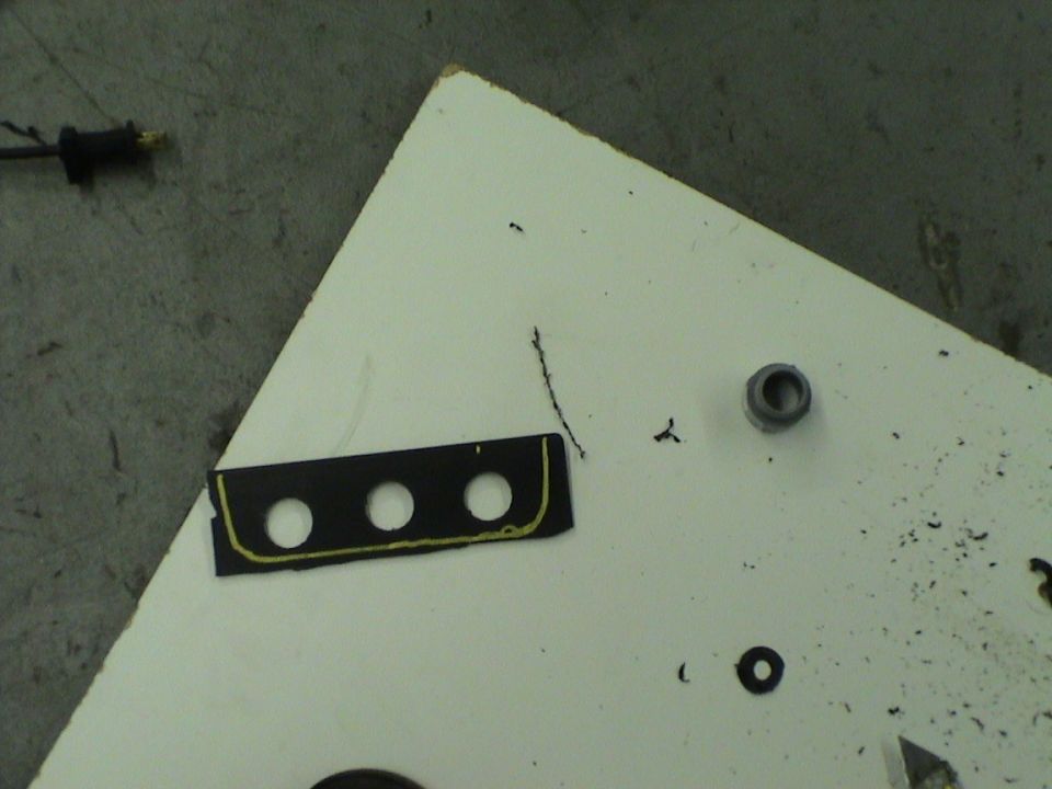 Black plastic trim piece with three circular cutouts and yellow trim, on a white surface
