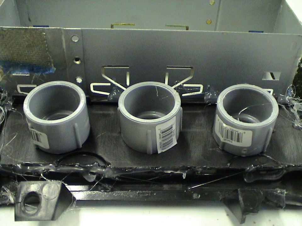 Three PVC pipe fittings attached to a metal bracket, likely for a custom car stereo or gauge setup